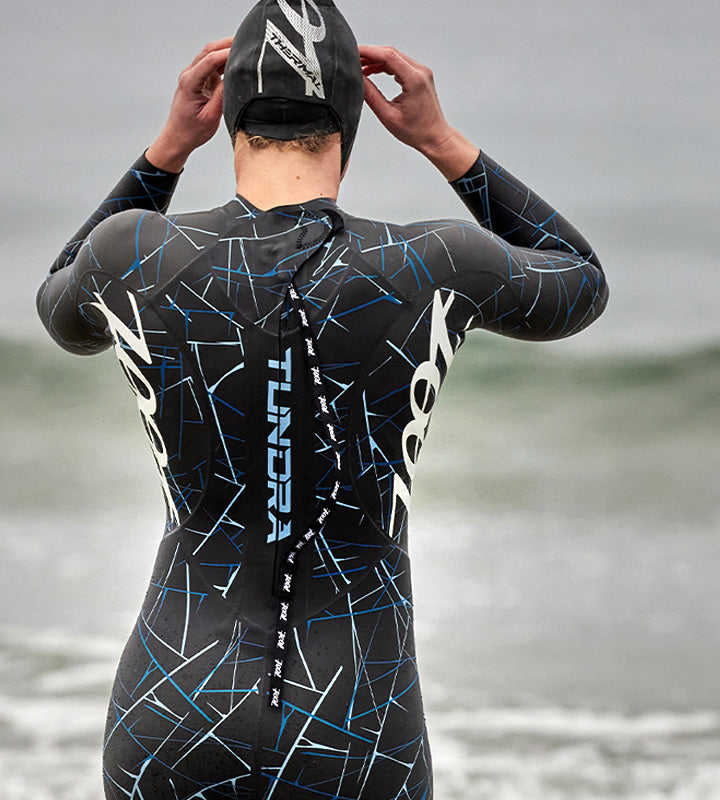 Female in Tundra wetsuit entering ocean